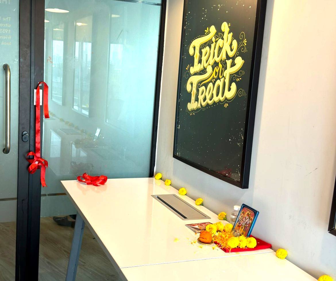 Ribbon tied to the office door with marigold flowers and a small shrine on the desk beside it