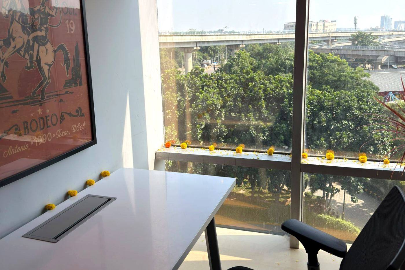 Desk beside a full-height window overlooking trees and the flyover